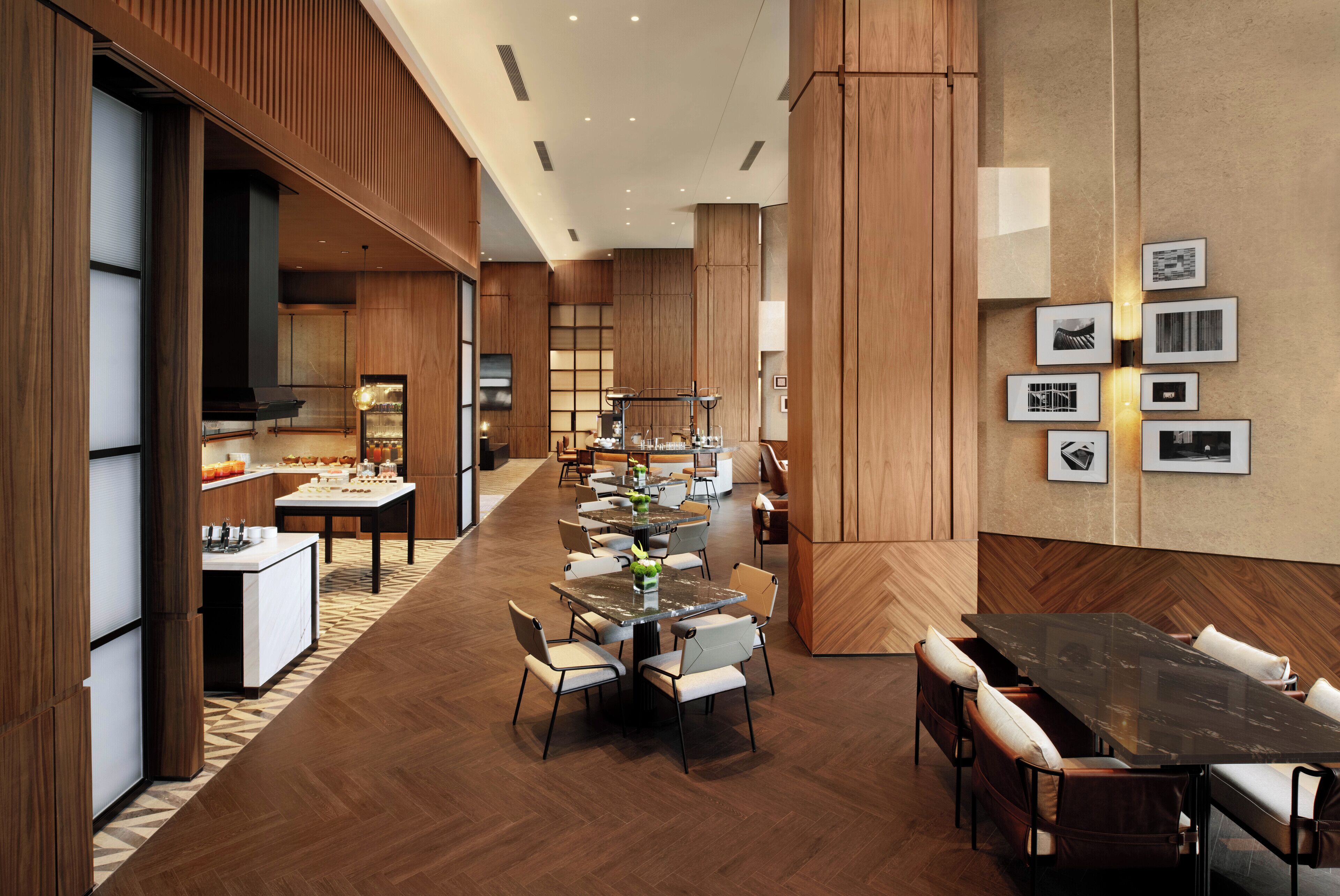 Un ampli vestíbul d'hotel amb diverses zones de restauració, panells de fusta i un disseny modern.