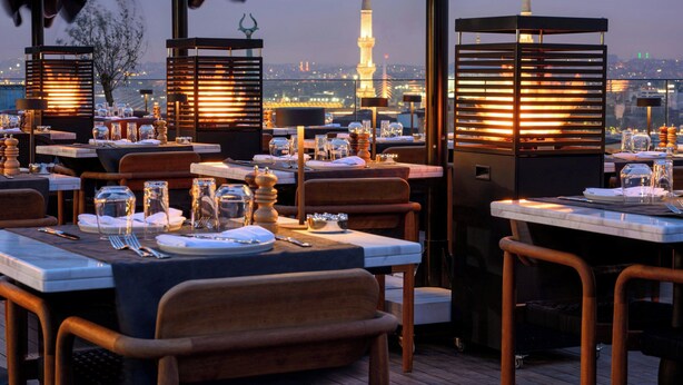 A rooftop restaurant with tables set for dining, overlooking a cityscape with a prominent tower. - Orient Occident Hotel Istanbul, Autograph Collection (Istanbul)