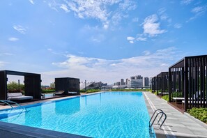A rooftop pool with lounge areas, a clear sky, and a city skyline in the background. - Zhuhai Marriott Hotel Jinwan (Zhuhai)