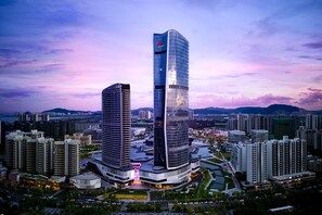 A modern high-rise building with a unique curved design, surrounded by other high-rise buildings in an urban setting. - Zhuhai Marriott Hotel Jinwan (Zhuhai)