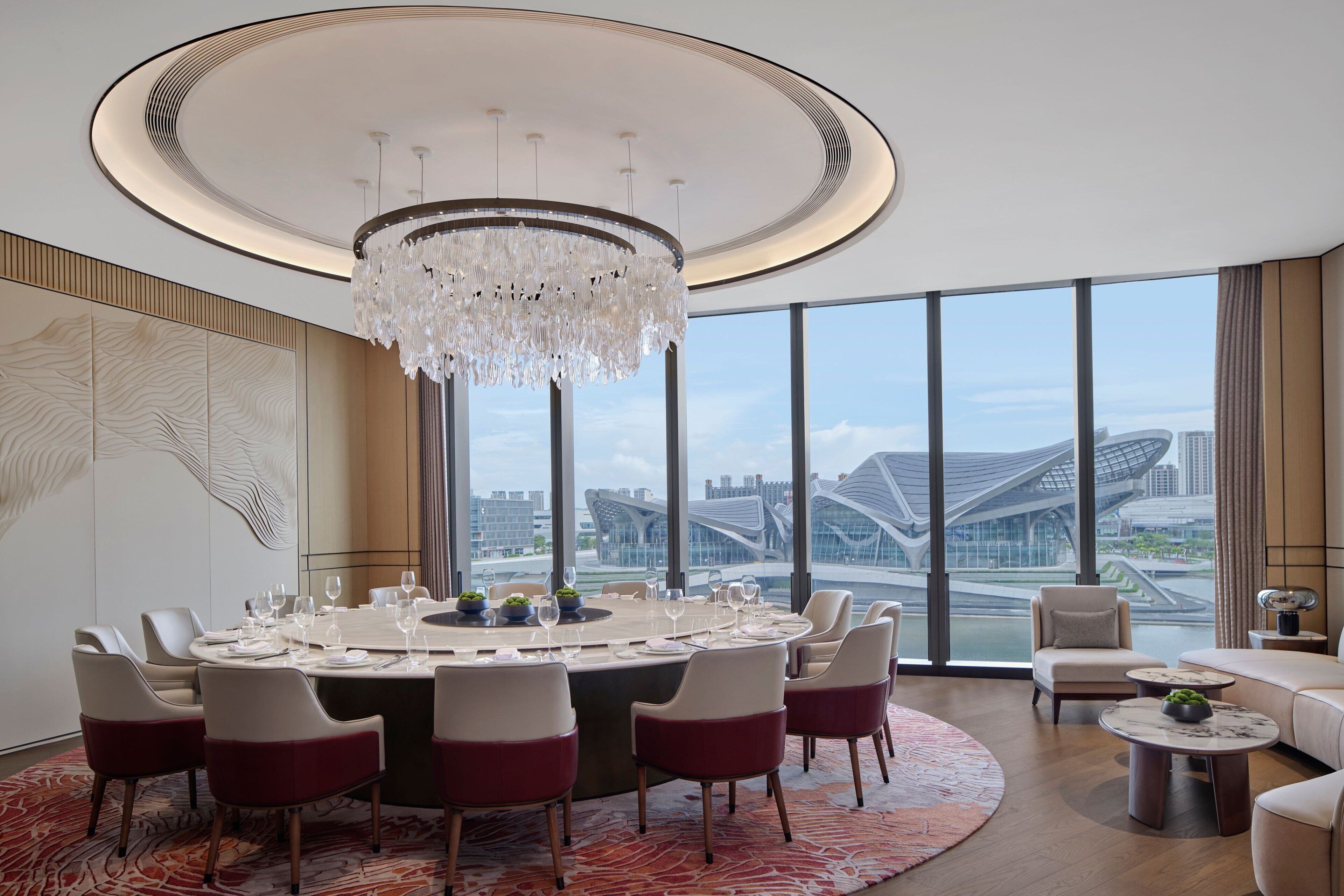 A modern dining area with a round table, chairs, and a chandelier.