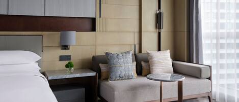 Una habitación de hotel moderna con una cama, un sofá, una mesita y una mesilla de noche.