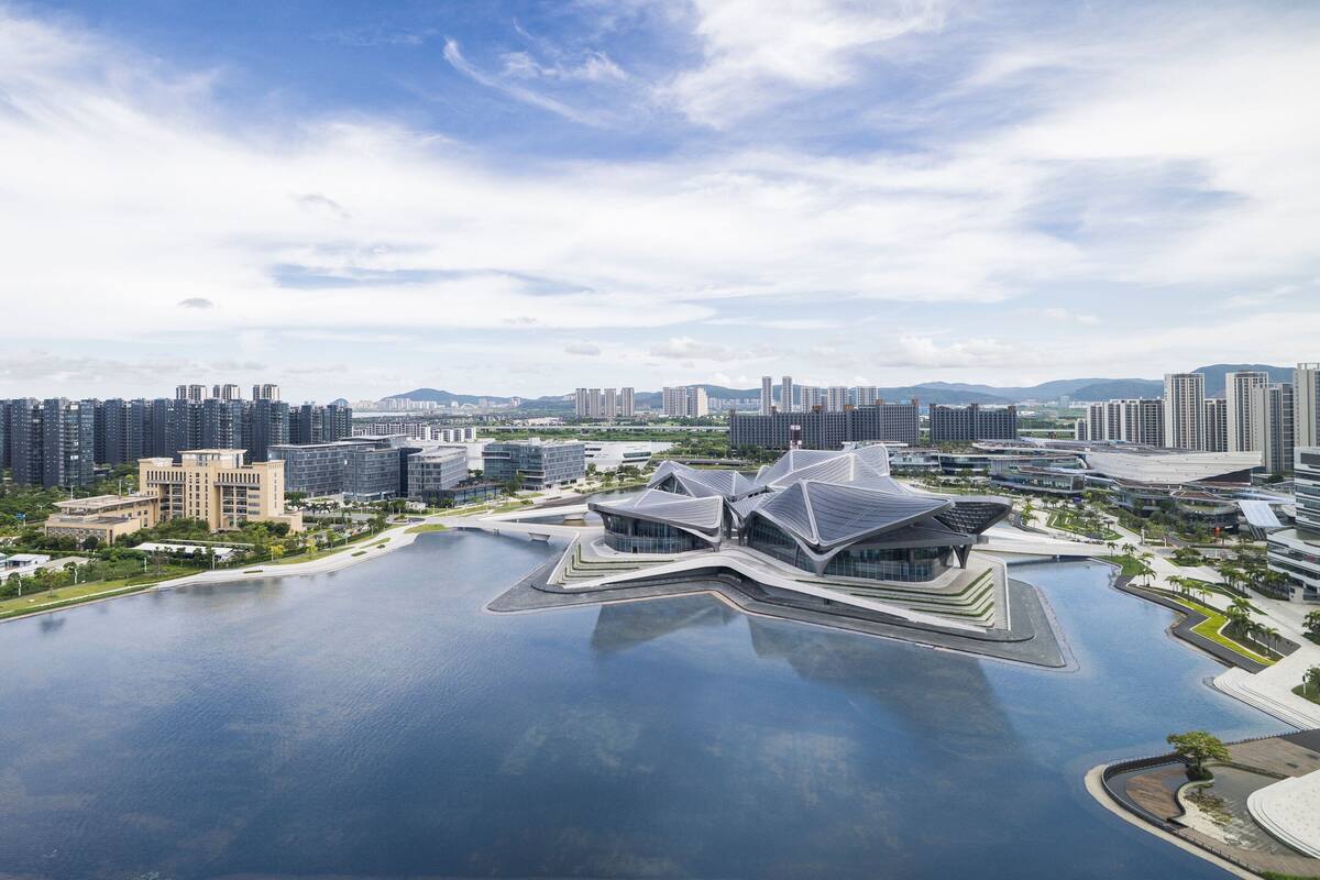 A modern architectural building with a unique star-shaped design, surrounded by a large body of water and a cityscape in the background.