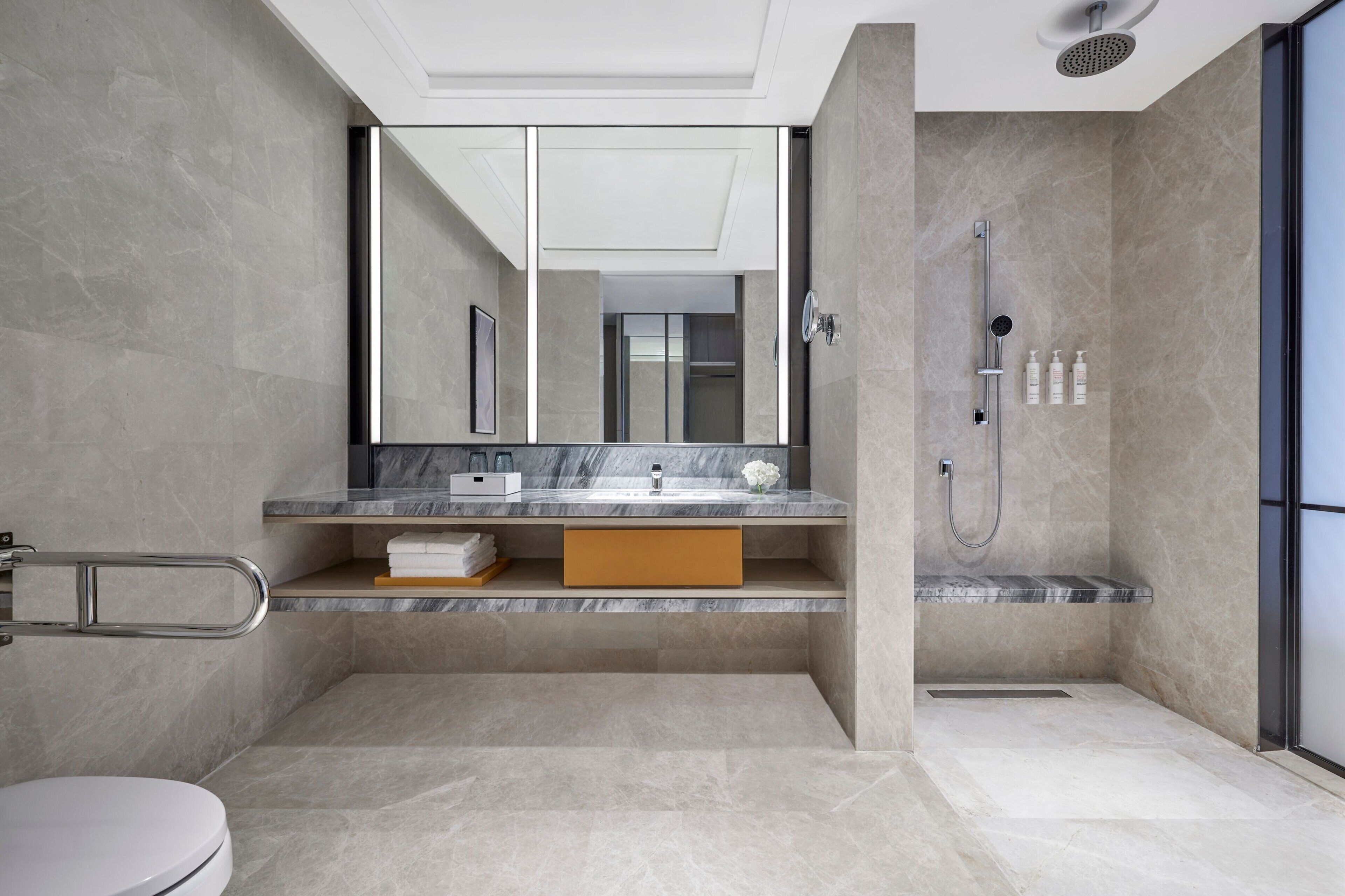 Une salle de bain moderne avec un grand miroir, une douche et des toilettes.