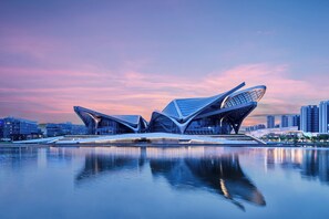 A modern architectural structure with a unique design, situated by a body of water with reflections. - Zhuhai Marriott Hotel Jinwan (Zhuhai)