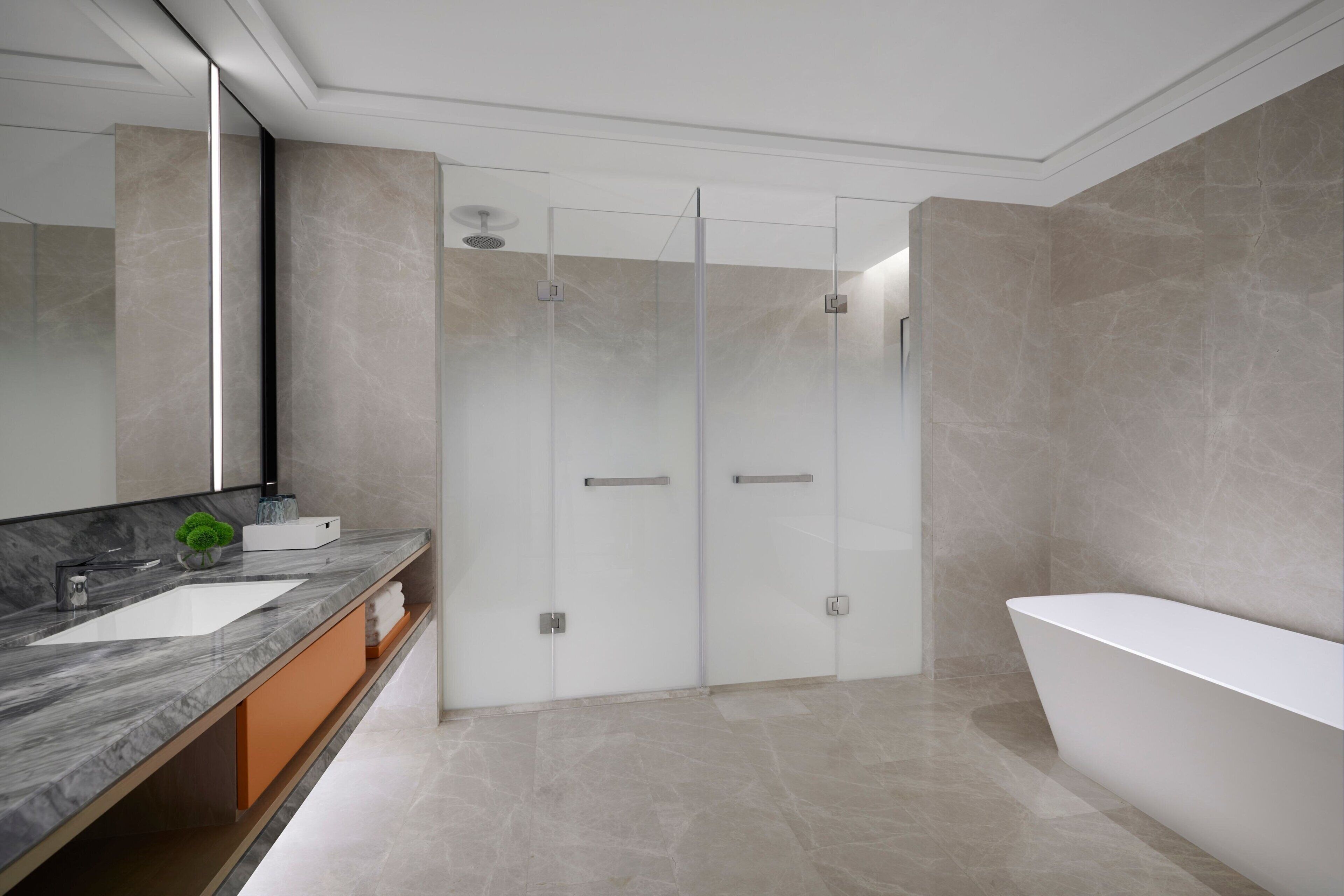 A modern bathroom with a large bathtub, a glass-enclosed shower, and a marble vanity.