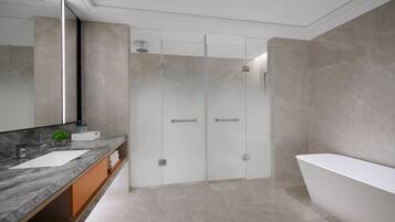 A modern bathroom with a large bathtub, a glass-enclosed shower, and a marble vanity.