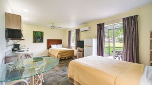 Habitación de hotel con una mesa de vidrio, dos camas, un televisor y vistas al exterior.