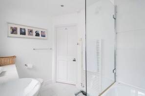 Ein modernes Badezimmer mit Toilette in Weiß, einer Duschkabine aus Glas und einer Bildercollage an der Wand.