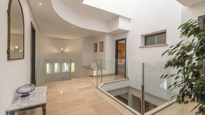 Un intérieur spacieux avec un plafond incurvé, une balustrade en verre et une table en marbre.