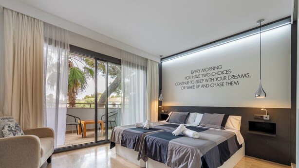 Une chambre moderne avec un grand lit, un canapé et une vue sur l’extérieur.