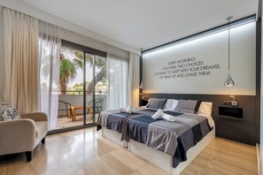 A modern bedroom with a large bed, a sofa, and a view of the outdoors.