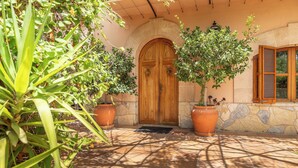 A building entrance with a wooden door, potted plants, and a tiled patio. - Villa Marjals - Eight Bedroom Villa, Sleeps 16 (Muro)