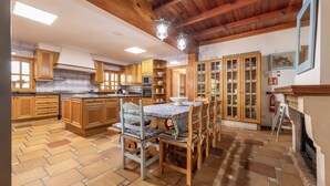 A spacious kitchen with wooden cabinets, a central island, and a dining area with chairs and a table. - Villa Marjals - Eight Bedroom Villa, Sleeps 16 (Muro)