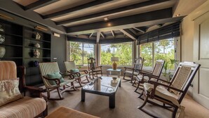 A spacious living room with a high ceiling, wooden rocking chairs, a glass coffee table, and a bookshelf with decorative items. - Villa Marjals - Eight Bedroom Villa, Sleeps 16 (Muro)