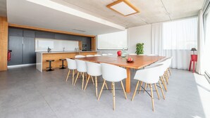 Une cuisine moderne avec un plan de travail en bois, des chaises blanches et une grande table à manger.