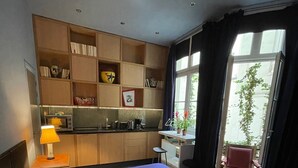 Et hotelværelse med en stor seng, et tekøkken, et spisebord og udsigt til det fri.