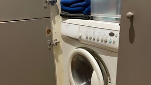 Et lille, moderne vaskerum med en frontbetjent vaskemaskine og et tørrestativ.