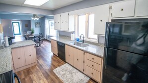 Une cuisine moderne avec des meubles en bois, un réfrigérateur noir et un plan de travail en granit.