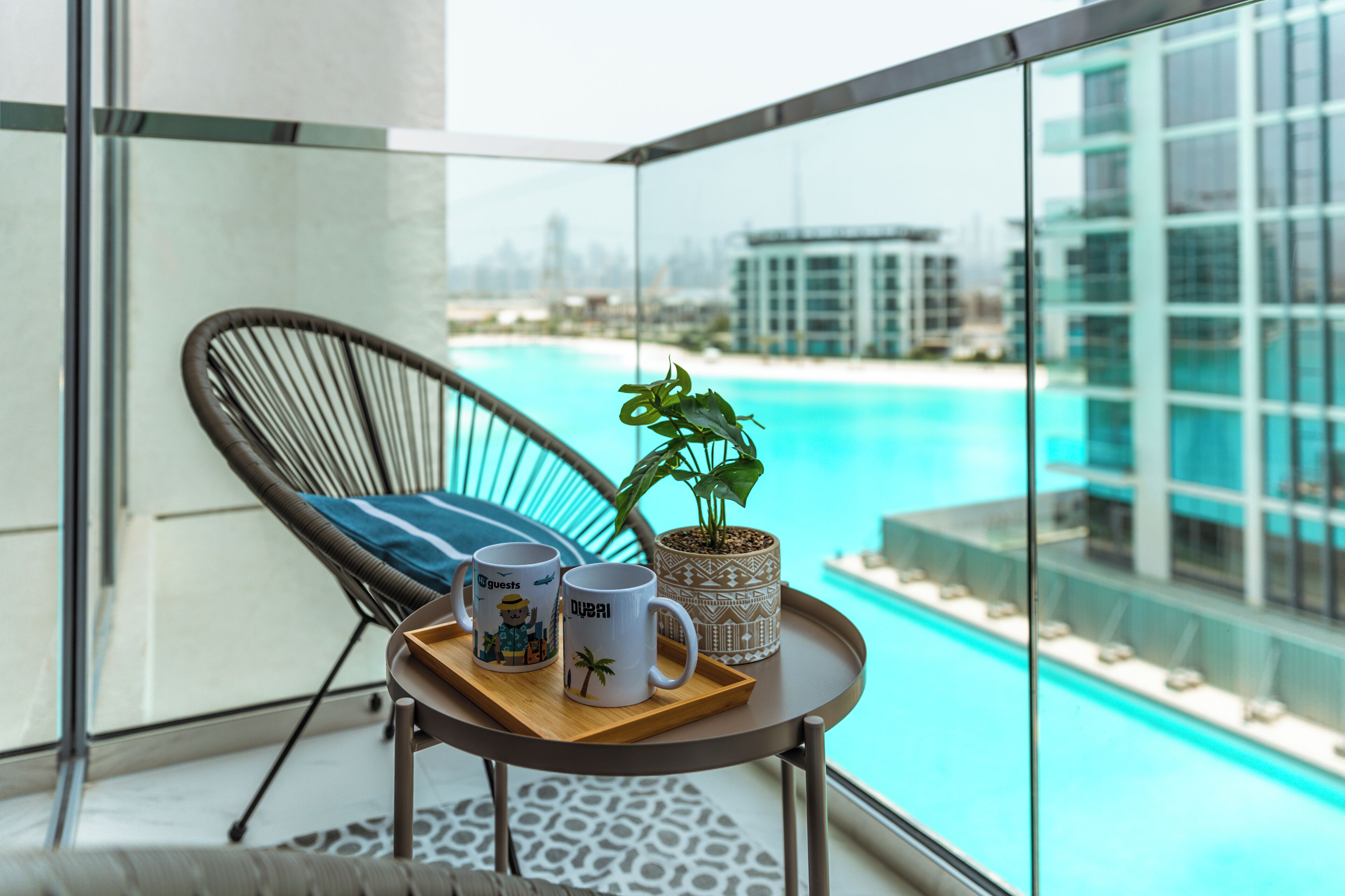 A balcony with a chair, two mugs, and a potted plant.