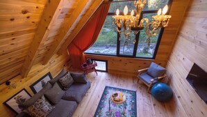 A cozy wooden interior with a sofa, a blue exercise ball, and a chandelier. - Nanu's Ayder Bungalow ve Kahvaltı (Rize)