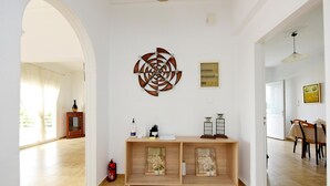 A spacious living area with a wooden console table, a decorative metal wall piece, and a dining area with a table and chairs. - Emerald Private Villa in Kalavarda Rhodes (Rhodes)