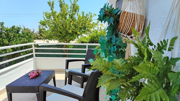 A balcony with wicker furniture, a small table with flowers, and green plants. - Emerald Private Villa in Kalavarda Rhodes (Rhodes)