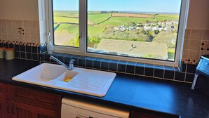 A kitchen with a large window offering a view of a rural landscape. - Family Escape | Garden, Parking, Pet friendly (Salcombe)