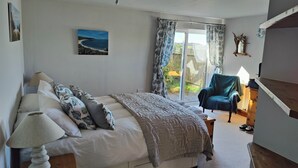 A bedroom with a bed, a chair, a lamp, a painting, and a view of the outdoors. - Family Escape | Garden, Parking, Pet friendly (Salcombe)