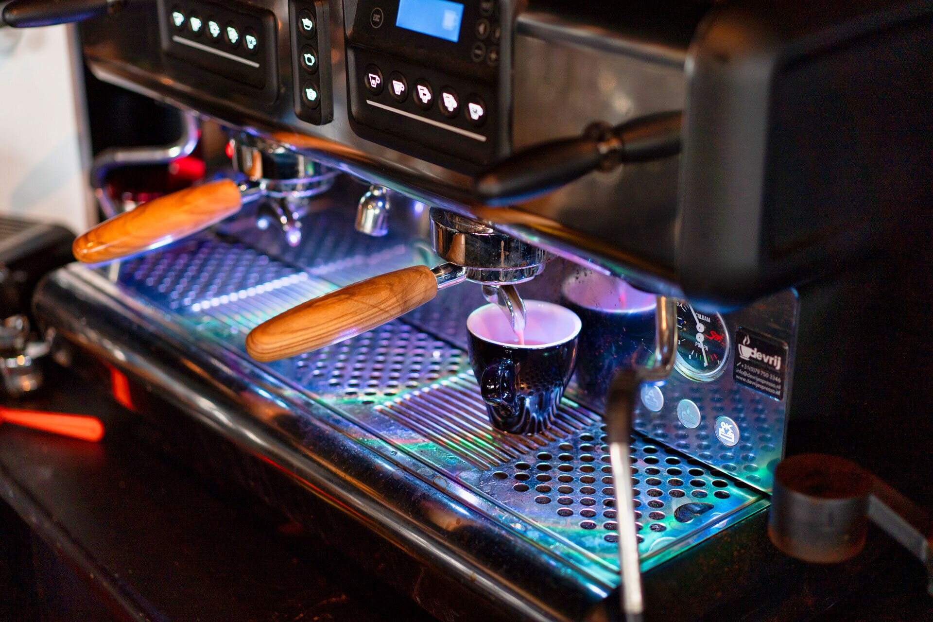 A coffee machine with a digital display and a milk frothing wand.