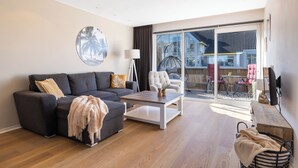 A modern living room with a sofa, coffee table, and a view of the outside balcony. - 2 bedroom apartment in breukelen (Breukelen)
