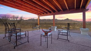 A covered outdoor seating area with metal chairs and tables, overlooking a desert landscape with mountains in the distance. - New Hillside Home overlooking Santa Cruz River Valley in Rio Rico near Tubac (Rio Rico)