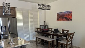 A kitchen with a stainless steel refrigerator, a dining table with chairs, a bench, a hanging light fixture, and a painting on the wall. - New Hillside Home overlooking Santa Cruz River Valley in Rio Rico near Tubac (Rio Rico)