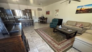 A spacious living area with a kitchen, dining table, and a sofa. - New Hillside Home overlooking Santa Cruz River Valley in Rio Rico near Tubac (Rio Rico)