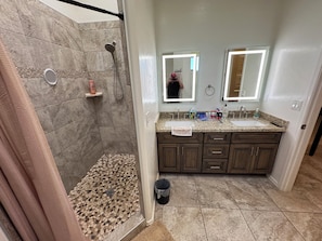 Un baño con ducha, tocador y dos espejos.