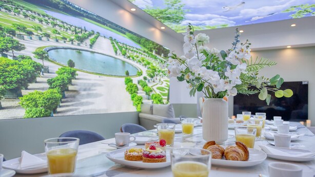 Un desayuno con un mural pintoresco, un centro de mesa floral blanco y una variedad de alimentos para el desayuno sobre la mesa.