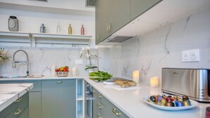 Una cocina moderna con encimeras de mármol, horno empotrado y refrigerador de acero inoxidable.
