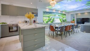 Una cocina moderna con una isla grande, un comedor con vistas a un jardín y un techo con proyección de cielo.