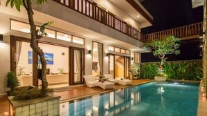 Ein modernes Hotel mit Pool, Liegestühlen und einer gut beleuchteten Außenansicht bei Nacht.