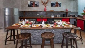 A kitchen with a central island, stools, and various kitchen appliances. - 2 BR Tranquil Villa 10 Min Walk to Seminyak Beach (Kuta Utara)