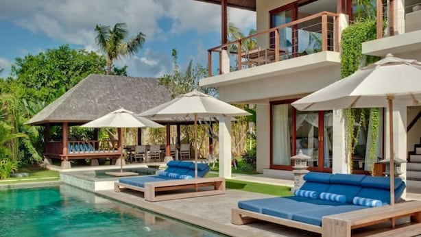 Un moderno resort con piscina, sillas de descanso y sombrillas.