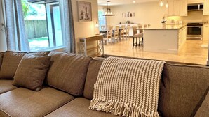 Un salon moderne avec un canapé et une vue sur une cuisine et un coin repas spacieux.