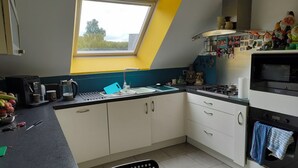 Una cucina compatta con una finestra sul tetto, una macchina da caffè e un fornello.
