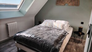 Una camera da letto con finestra a lucernario, un letto con cuscini, un comodino con una lampada e un elemento decorativo a parete.