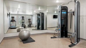 A gym with exercise equipment, a mirrored wall, and exercise balls.