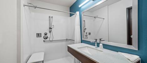 Un baño moderno con ducha, lavamanos y espejo.