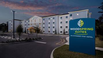 A hotel with a sign reading 'Woodspring Suites' and 'An Extended Stay Hotel.'