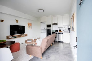 Un espace de vie compact comprenant un canapé, un téléviseur et une kitchenette.