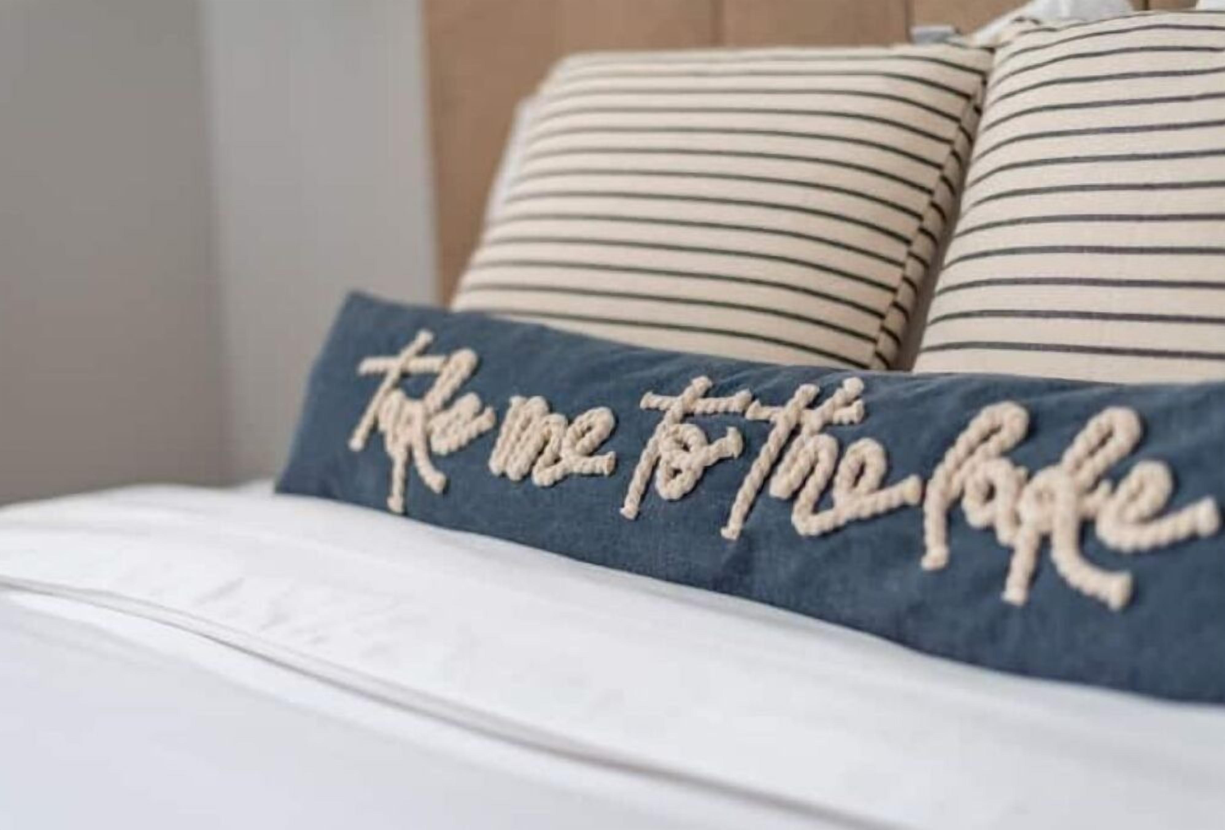 A bed with a pillow featuring embroidered text.