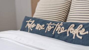 A bed with a pillow featuring embroidered text.
